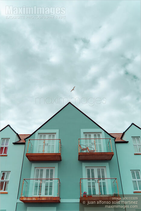 Stock photo of Cute blue residential houses with balconies under blue sky Buy commercial use license at MaximImages