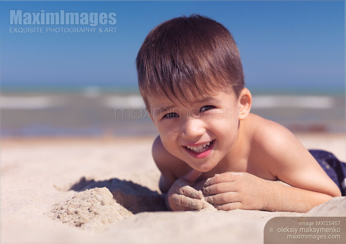 Stock photo of Cute little boy playing in the sand on a beach Buy commercial use license at MaximImages