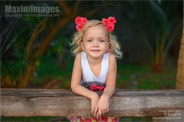 Stock photo of Cute smiling little girl with pink flowers in her blond hair Buy commercial use license at MaximImages