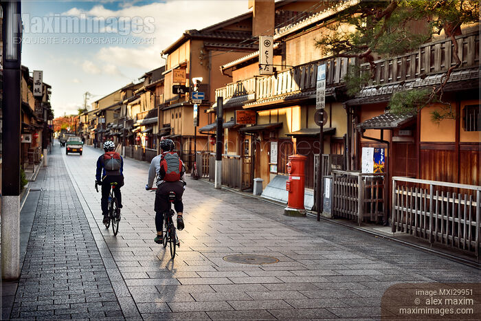 Stock photo of Cyclists on Hanamikoji Dori street in Gion district in the morning Kyoto Japan Buy commercial use license at MaximImages