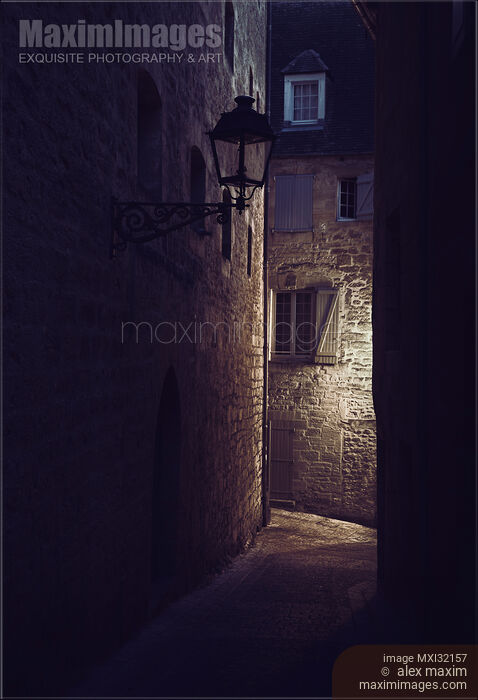 Stock photo of Dark old street with stone houses in a medieval French town at night Buy commercial use license at MaximImages