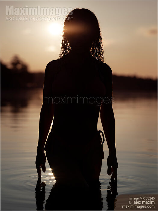 Dark silhouette of a woman coming out of the water after bathing in a sea at sunset Stock photo of Dark silhouette of a woman coming out of the water after bathing in a sea at sunset Buy commercial use license at MaximImages