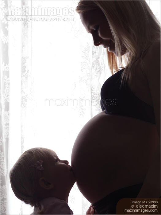 Daughter Kissing Her Pregnant Mother's Belly Stock photo of Daughter Kissing Her Pregnant Mother's Belly Buy commercial use license at MaximImages
