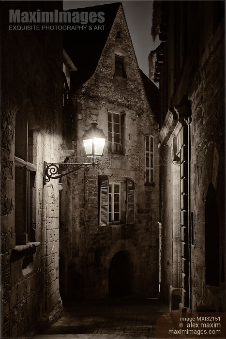 Stock photo of Dramatic fine art nighttime scenery of an old street lit by a lamp in a French medieval town Buy commercial use license at MaximImages