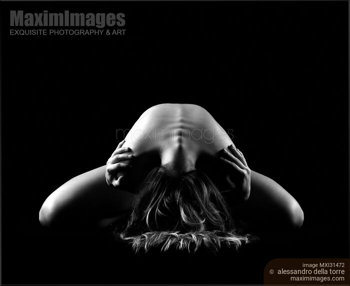 Stock photo of Dramatic nude figure of a woman leaning forward arching her back Buy commercial use license at MaximImages
