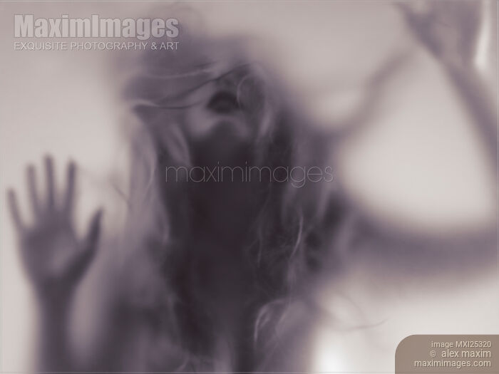 Stock photo of Dramatic photo of woman blurred silhouette behind hazy glass Buy commercial use license at MaximImages