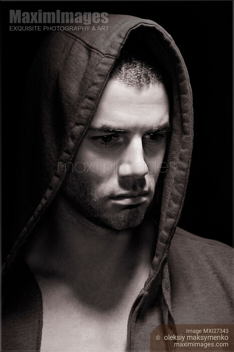 Stock photo of Dramatic portrait of a man in a hoodie with serious expression on his face Buy commercial use license at MaximImages