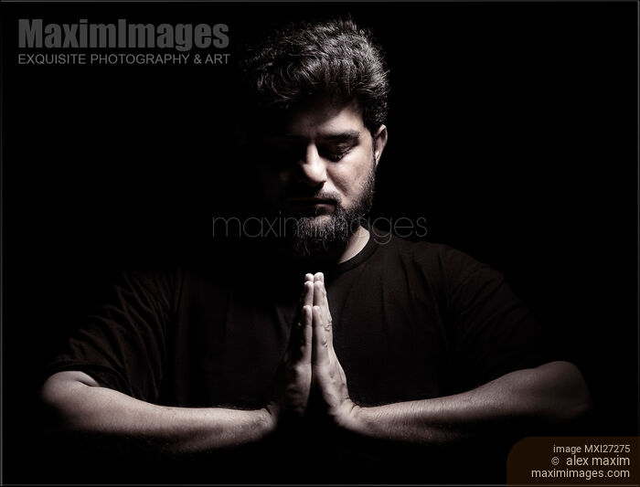 Stock photo of Dramatic portrait of a man with hands folded in prayer Buy commercial use license at MaximImages