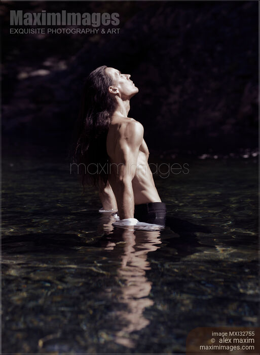 Stock photo of Dramatic portrait of a shirtless man with bare torso standing in water in pants Buy commercial use license at MaximImages