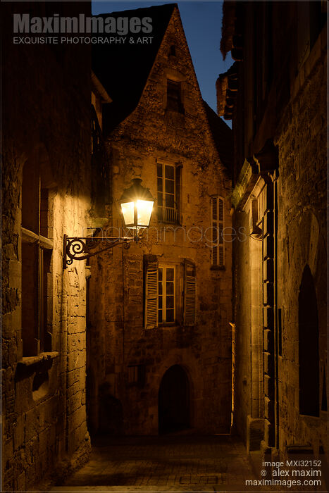 Stock photo of Dramatic twilight scenery of an old French street with stone houses lit by a street lamp Buy commercial use license at MaximImages