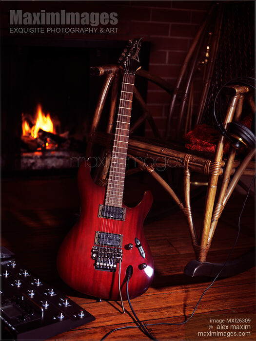 Stock photo of Electric guitar propped on chair near fireplace Buy commercial use license at MaximImages