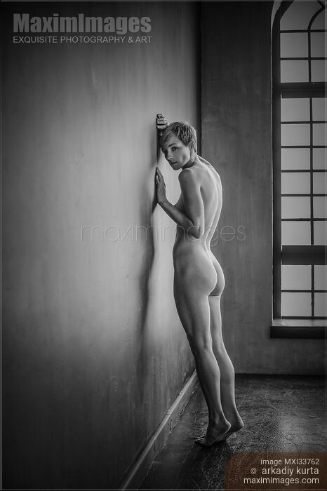 Stock photo of Expressive art nude portrait of a woman with short hair standing naked leaning against bare wall Buy commercial use license at MaximImages