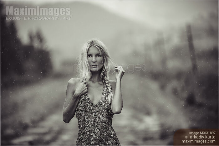 Expressive portrait of a blond woman in a summer dress standing on country road Stock photo of Expressive portrait of a blond woman in a summer dress standing on country road Buy commercial use license at MaximImages