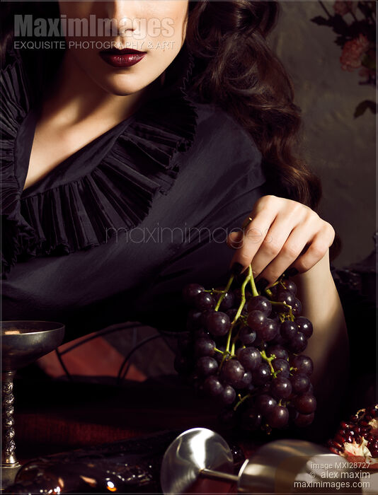 Femme fatale woman with dark lips holding black grapes in her hand Stock photo of Femme fatale woman with dark lips holding black grapes in her hand Buy commercial use license at MaximImages