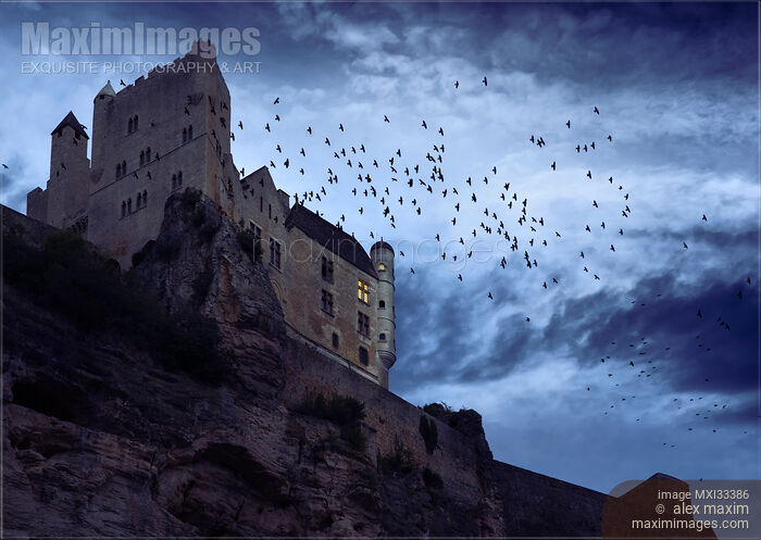 Stock photo of Flock of crows over a French stone castle on a mountain cliff under dramatic stormy night sky Buy commercial use license at MaximImages
