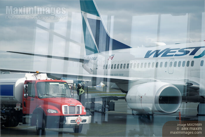 Stock photo of Fuel tanker track refueling WestJet airplane before flight at airport Buy commercial use license at MaximImages