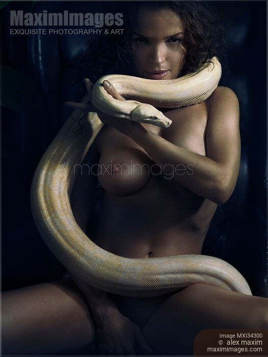 Stock photo of Gorgeous mysterious powerful woman with large white boa snake coiled around her sexy naked body in shadows Buy commercial use license at MaximImages