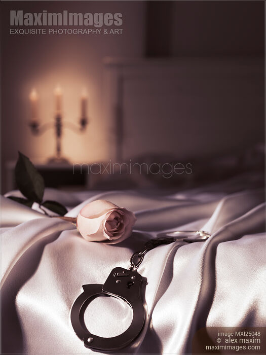Handcuffs and a rose on bed Romantic suggestive still life Stock photo of Handcuffs and a rose on bed Romantic suggestive still life Buy commercial use license at MaximImages