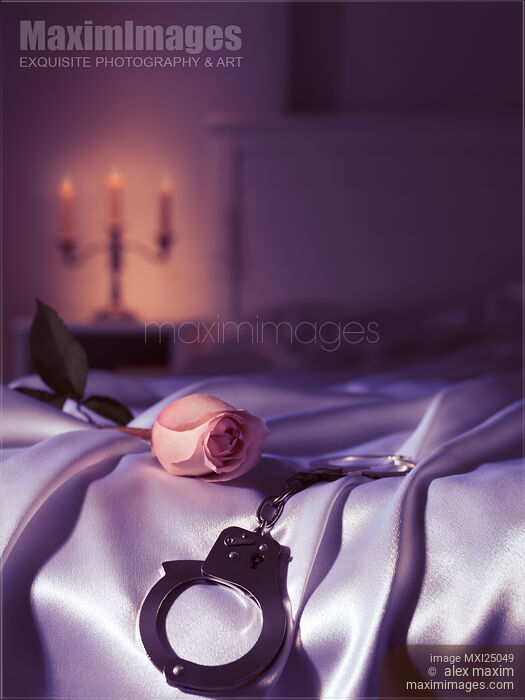Stock photo of Handcuffs and a rose on bed. Suggestive intimate scene still life. Buy commercial use license at MaximImages