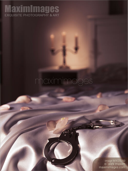 Handcuffs and rose petals on bed artistic suggestive bondage concept Stock photo of Handcuffs and rose petals on bed artistic suggestive bondage concept Buy commercial use license at MaximImages