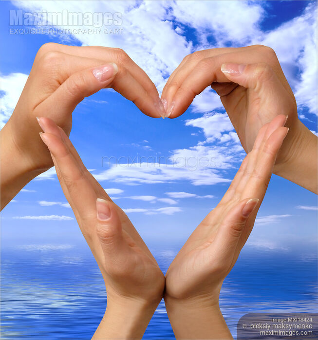Stock photo of Hands Making Heart Symbol over Blue Sky Buy commercial use license at MaximImages