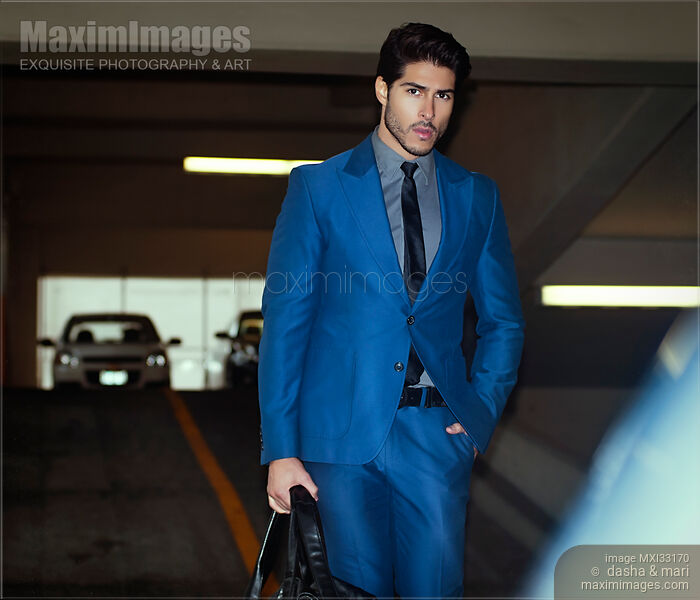 Handsome man in a classic elegant blue business suit walking to his car in indoor parking lot Stock photo of Handsome man in a classic elegant blue business suit walking to his car in indoor parking lot Buy commercial use license at MaximImages