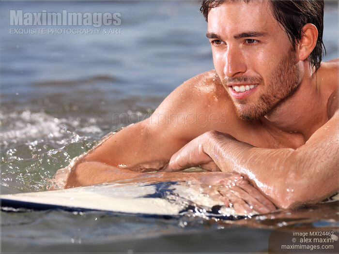 Happy young man with surfboard in water Stock photo of Happy young man with surfboard in water Buy commercial use license at MaximImages