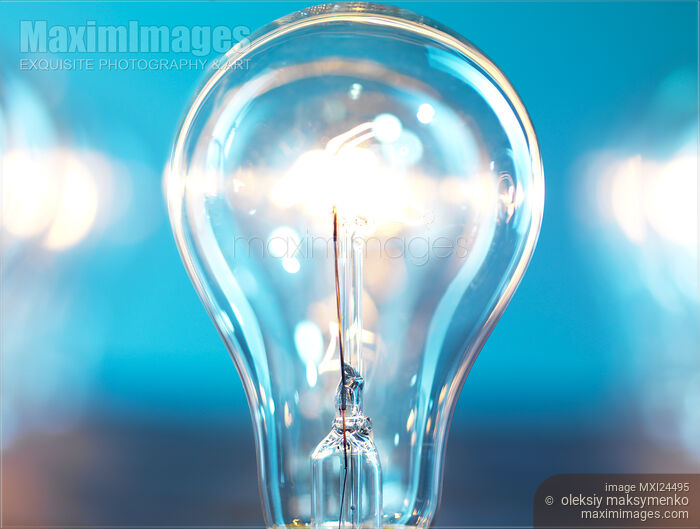 Stock photo of Illuminated light bulb on blue background Buy commercial use license at MaximImages