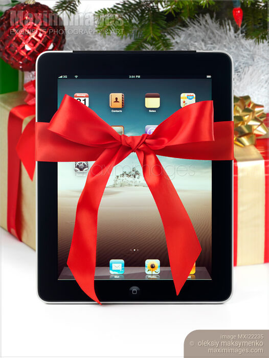 Stock photo of iPad with a Gift Bow under a Christmas Tree Buy commercial use license at MaximImages