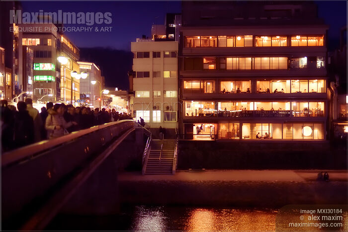 Stock photo of Izumoya Japanese restaurant in Kyoto with windows lit up at night and people dining inside Buy commercial use license at MaximImages