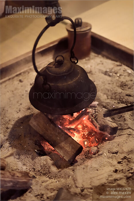 Stock photo of Japanese cast iron kettle Kama on burning firewood in floor hearth Buy commercial use license at MaximImages