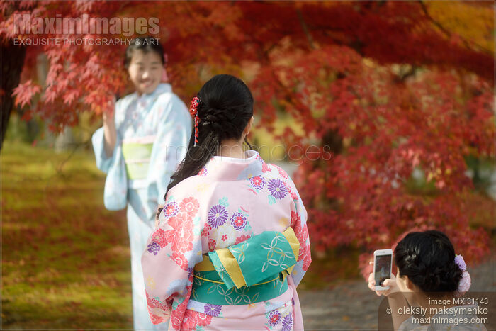 Stock photo of Japanese girls in colorful yukatas taking pictures in Kyoto autumn scenery Buy commercial use license at MaximImages