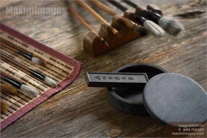 Stock photo of Japanese sumi-e painting art tools brushes ink stone and black ink stick on rustic wooden table Buy commercial use license at MaximImages