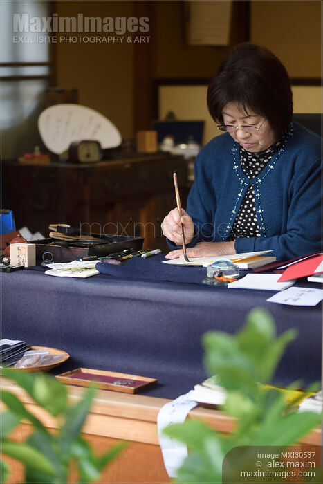 Stock photo of Japanese woman calligrapher writing at a desk Buy commercial use license at MaximImages