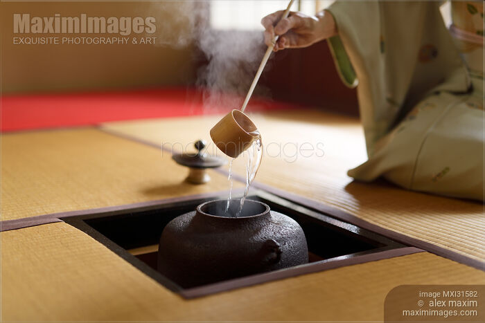 Stock photo of Japanese woman tea ceremony master pouring hot water from a pot with a ladle in a traditional teahouse Buy commercial use license at MaximImages