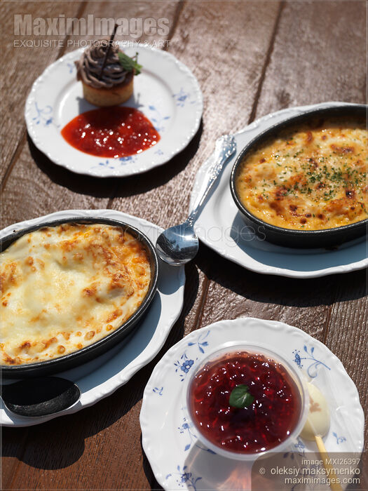 Stock photo of Lasagna and casserole dish with dessert on table Buy commercial use license at MaximImages