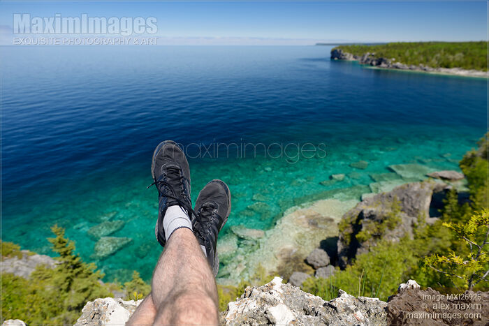 Stock photo of Legs of a person sitting on a cliff of Georgian Bay in Canada Buy commercial use license at MaximImages