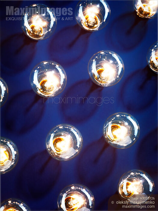 Stock photo of Lit light bulbs on blue background Buy commercial use license at MaximImages