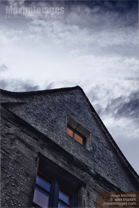 Lit up gable wall attic window of an old house at night under dramatic cloudy sky Stock photo of Lit up gable wall attic window of an old house at night under dramatic cloudy sky Buy commercial use license at MaximImages