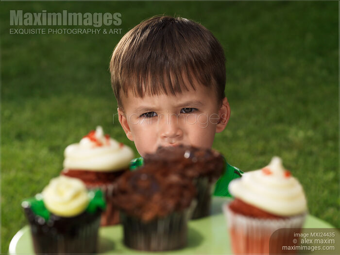Stock photo of Little boy wants to eat all the cupcakes Buy commercial use license at MaximImages
