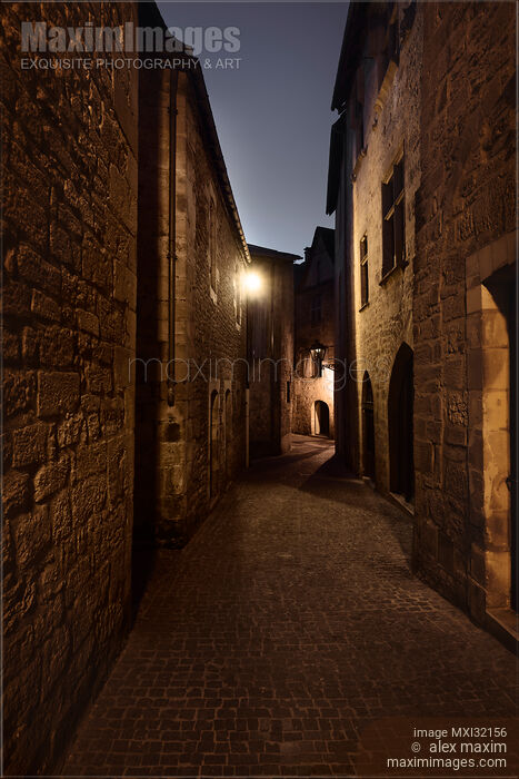 Stock photo of Long narrow old cobbled street with French stone houses in twilight Buy commercial use license at MaximImages