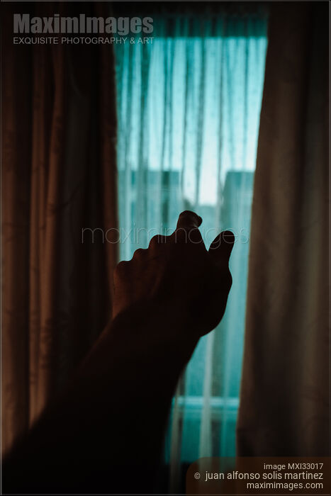 Stock photo of Male hand reaching towards the window from darkness of a house Buy commercial use license at MaximImages