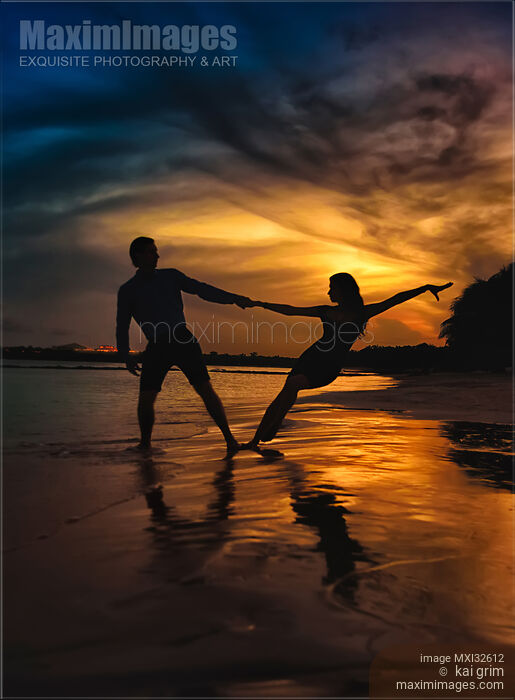 Stock photo of Man and woman dancing at a seashore in dramatic sunset Couple holding hands dark silhouette against sunset sky Buy commercial use license at MaximImages