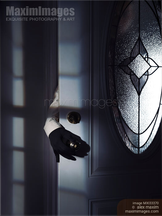 Man hand in a black gloves reaching for a door handle from behind a door in a dark shadowy house Stock photo of Man hand in a black gloves reaching for a door handle from behind a door in a dark shadowy house Buy commercial use license at MaximImages