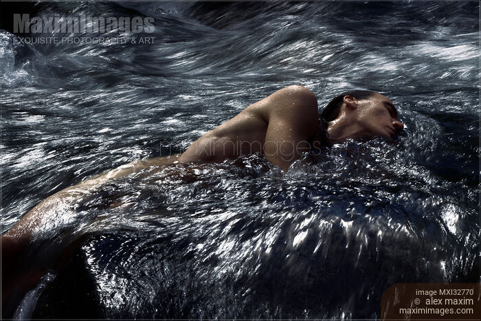 Stock photo of Man lying half submerged in turbulent water of a river stream in dramatic tranquil nature scenery Buy commercial use license at MaximImages