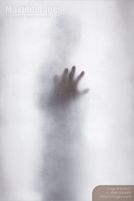 Stock photo of Man with outstretched hand touching hazy glass surface out from a bright white light Buy commercial use license at MaximImages