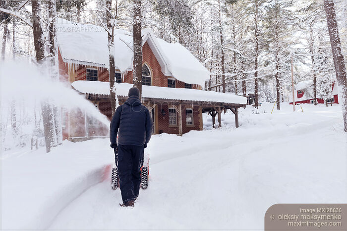 Stock photo of Man with snow blower clearing driveway in Canadian winter Buy commercial use license at MaximImages