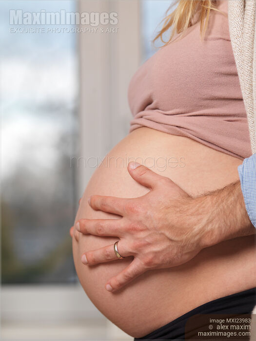 Stock photo of Man's hands on pregnant woman's belly Buy commercial use license at MaximImages