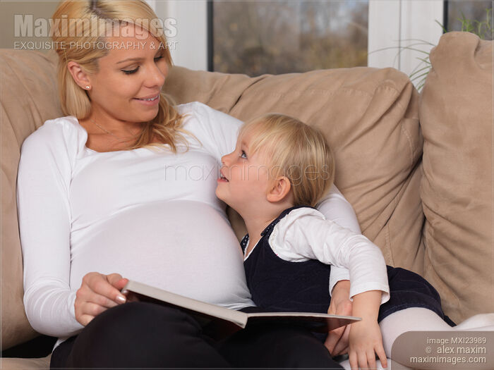 Stock photo of Mother and her little daughter reading a book together Buy commercial use license at MaximImages