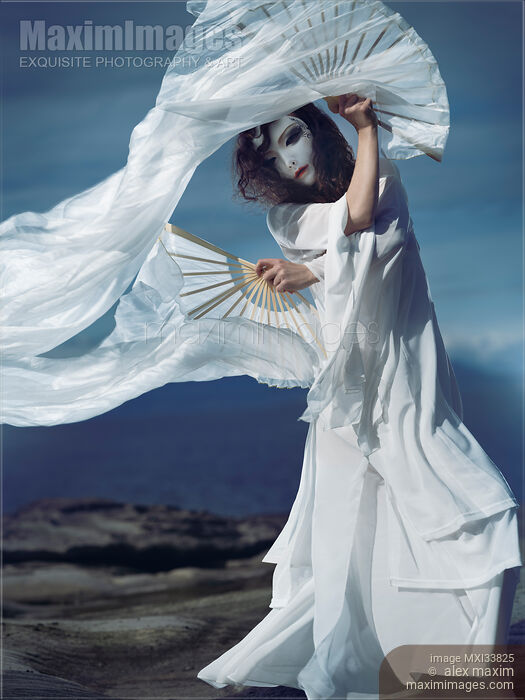 Mysterious asian woman in oriental theatrical face mask and flowy white dress dancing gracefully with silk fans Stock photo of Mysterious asian woman in oriental theatrical face mask and flowy white dress dancing gracefully with silk fans Buy commercial use license at MaximImages
